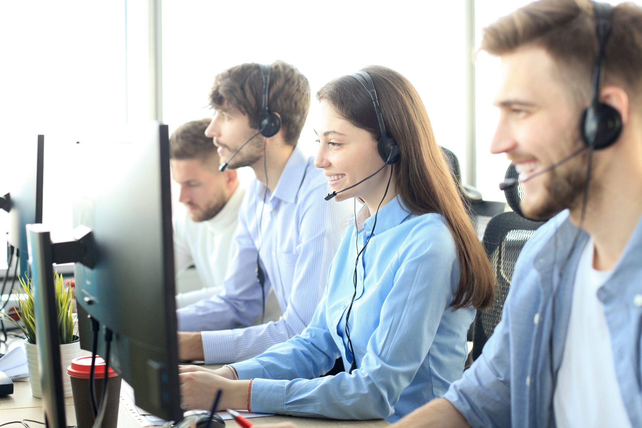 Portrait of call center agents accompanied by her team. Smiling customer support operator at work.